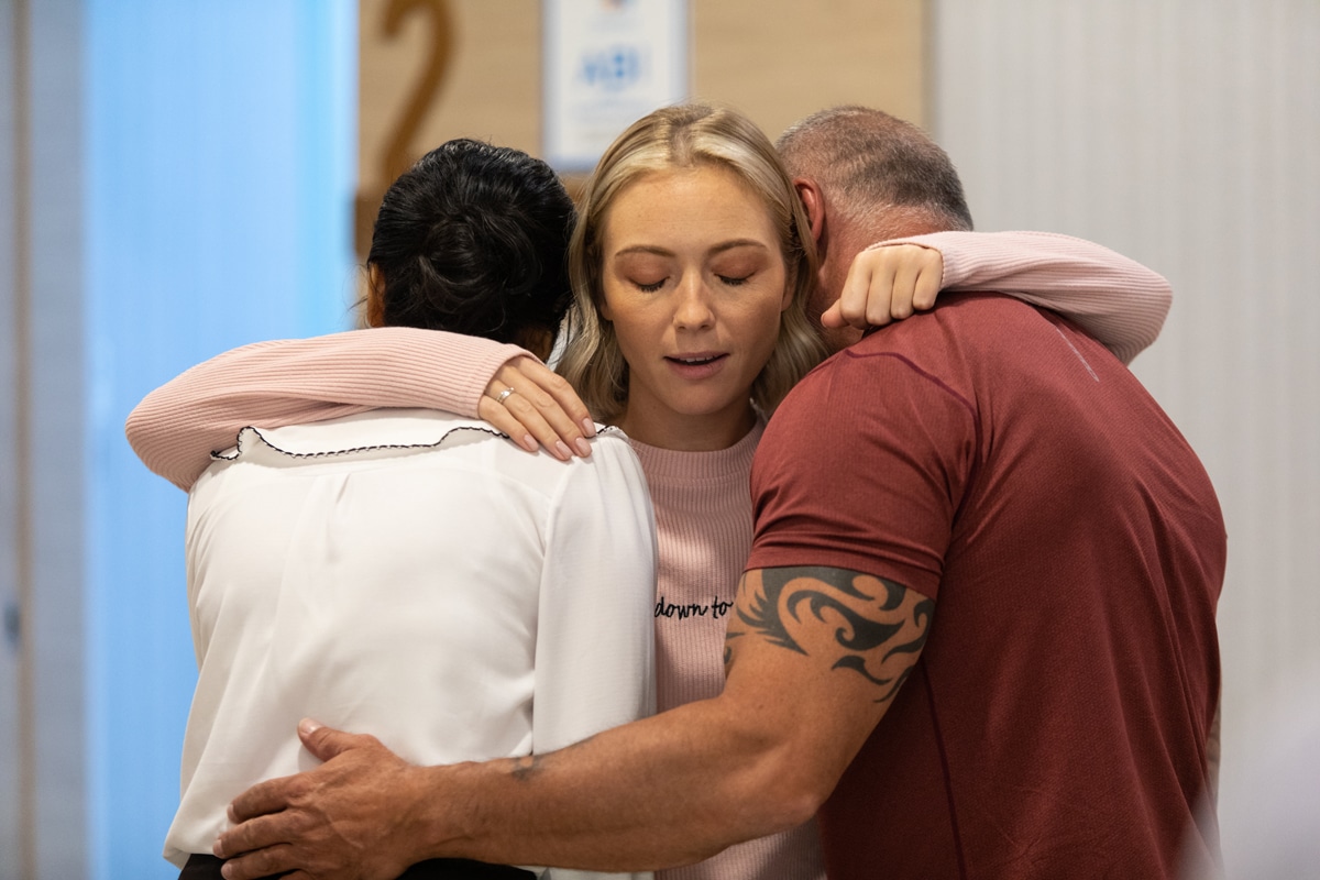 A mother and father embracing their daughter who is going through mental health treatment