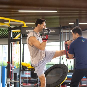 A man practicing Muay Thai kicking with a personal fitness trainer.