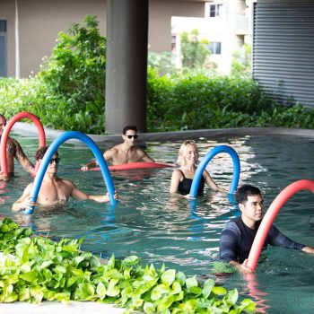 People in a pool participating in water exercises with a fitness trainer.